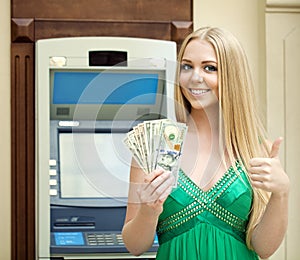 Blonde woman in a green dress is holding a cash dollars