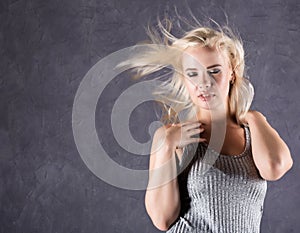 Blonde woman with hair in the wind. girl with flying hair on a gray background