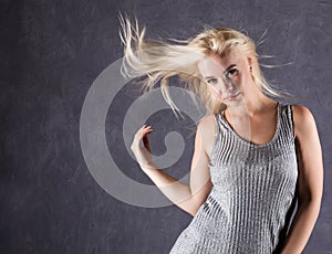 Blonde woman with hair in the wind. girl with flying hair on a gray background