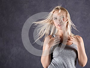 Blonde woman with hair in the wind. girl with flying hair on a gray background