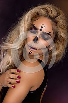 blonde woman in Halloween makeup and leather outfit on a black background in the studio. Skeleton, monster