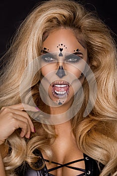 blonde woman in Halloween makeup and leather outfit on a black background in the studio. Skeleton, monster