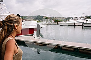 Blonde woman in a harbour looking at moored yachts