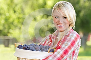 A Blonde Woman Holding a Basket of Plums