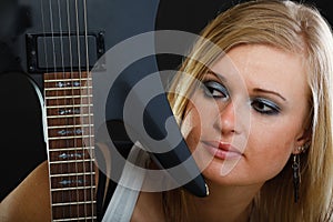 Blonde woman holding electric guitar, black background