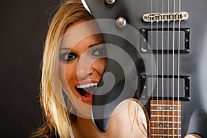 Blonde woman holding electric guitar, black background