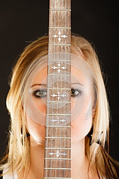 Blonde woman holding electric guitar, black background