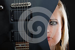 Blonde woman holding electric guitar, black background