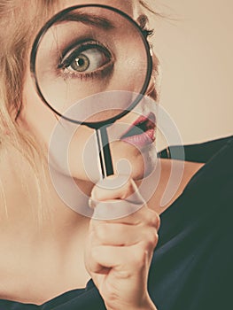 Woman holding magnifying glass investigating photo