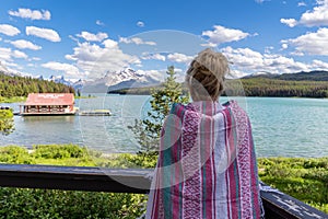 Blonde woman holds up a pink blanket while enjoying the view of Maligne Lake in Jasper National Park Alberta Canada