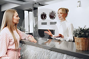 Blonde woman hotel guest checking-in at front desk in hotel