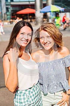 Blonde woman hugs her friend and smiles at camera