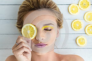 Blonde woman laying next to slices of lemon