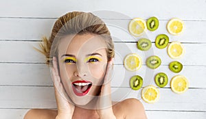 Blonde woman laying next to slices of lemon and kiwi