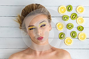 Blonde woman laying next to slices of lemon and kiwi
