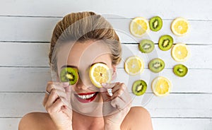 Blonde woman laying next to slices of lemon and kiwi