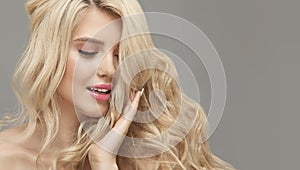 Blonde woman with long curly beautiful hair, studio shot on beige isolated with free copy space.