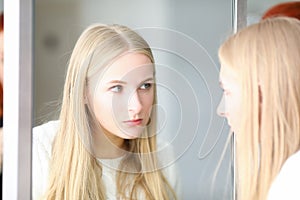 Blonde woman looking at mirror, beauty studio