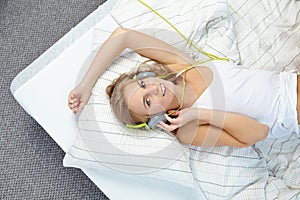 Rubio una mujer acostada sobre el una cama mientras escuchando música 