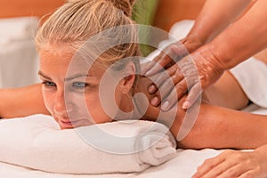 Blonde woman lying down and enjoying a massage given by two hands . Well-being and leisure concept
