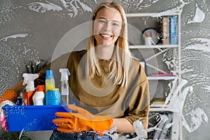 Blonde woman maid holding basket full of cleaning products