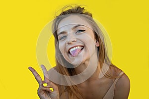 Blonde woman making funny face. positive girl acts on the camera, blinks, sticks out her tongue.