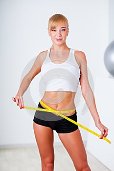 Blonde woman measuring her waistline