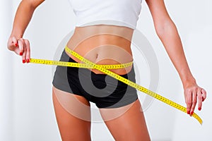 Blonde woman measuring her waistline