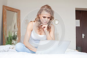 Blonde woman paying bills on laptop at home