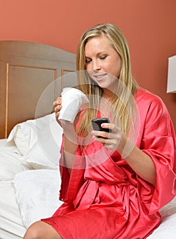 Blonde woman on phone holding coffee wearing robe