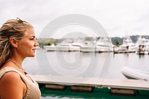 Blonde woman in a pier looking at moored yachts