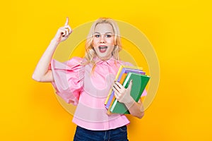 Blonde woman in pink blouse with pile of books