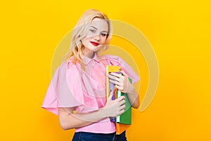 Blonde woman in pink blouse with pile of books