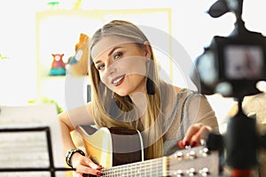 Blonde woman playing guitar live on camera