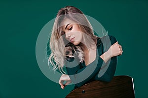 Blonde woman posing in green dress on green background