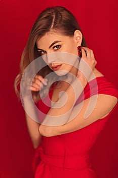 Blonde woman posing in red dress on red background