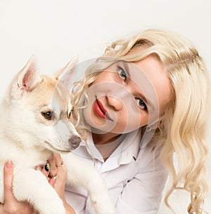 Blonde woman with puppy husky dog on a white sofa. girl playing with a dog