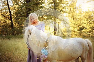 Woman in purple dress hugging white unicorn horse. Dreams come true. Fairy tale