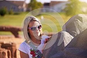 Blonde Woman Purple Sunglasses Behind Boulder
