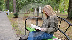 Blonde Woman Reading Book on Brench in Autumn Park.
