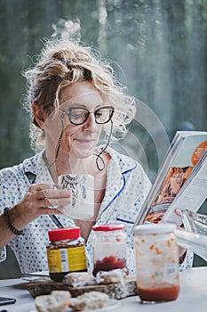 Blonde woman reading a magazine at breakfast time.