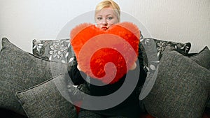 Blonde woman with red pillow heart shaped.