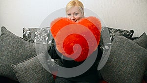 Blonde woman with red pillow heart shaped.