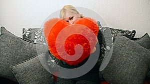 Blonde woman with red pillow heart shaped. Saint Valentine and International Women`s Day, Eight 8 March