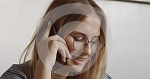 Blonde woman`s portrait talking on mobile smartphone closep