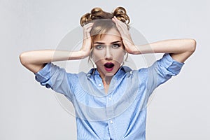 Blonde woman screaming with shock, holding hands on her head.