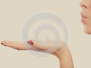 Blonde woman sending air kiss on palm hand