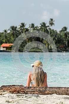 Blonde woman sitting on an idyllic tropical beach
