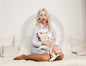 Blonde woman sitting on a sofa with puppy husky dog. girl playing with a dog