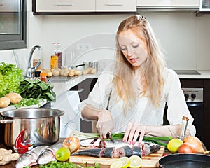 Blonde woman slicing raw fish photo